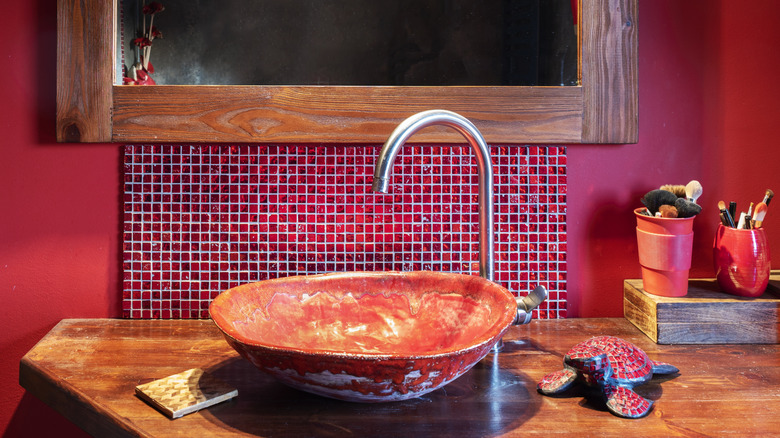 close up of all red bathroom with wood vanity and red marble sink bowl