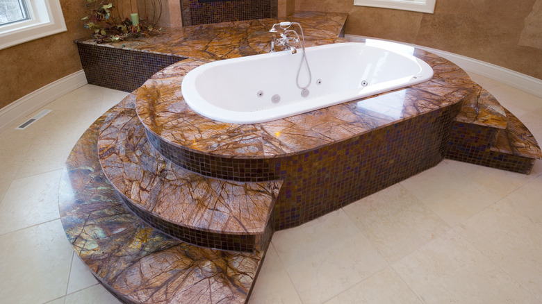 red marble bathtub and surround next to a red marble fireplace