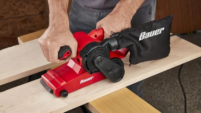 Person using a belt sander on wood