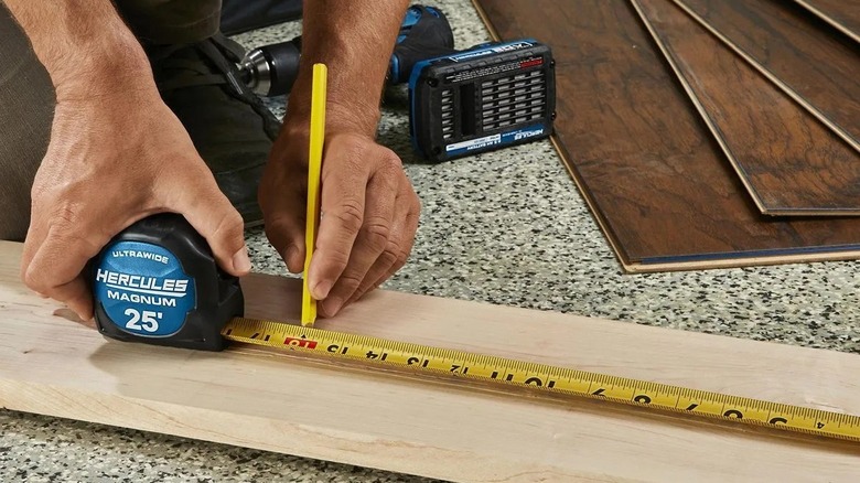 Person using a tape measure on a board