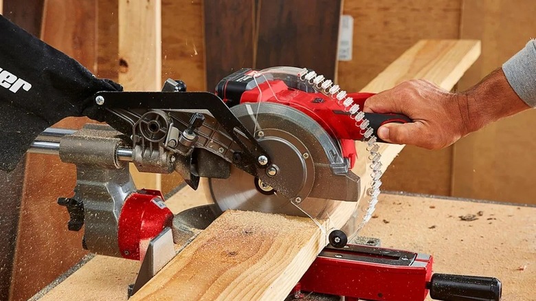 Person cutting a board with a miter saw