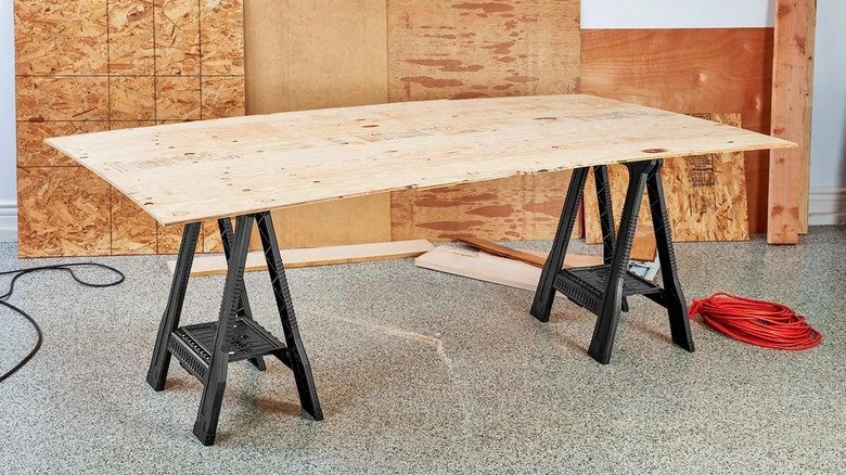 Sheet of plywood supported by two sawhorses
