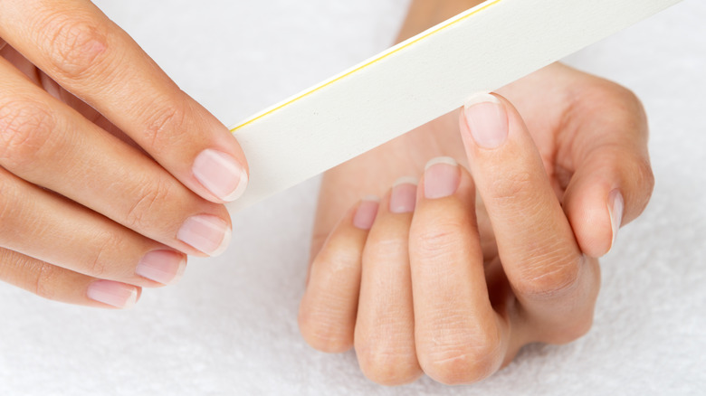 person filing nails with white file