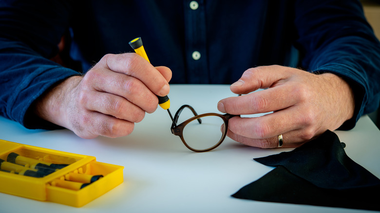 person screwing glasses frame