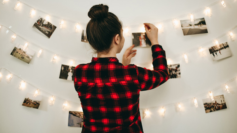 woman hanging photos on wall