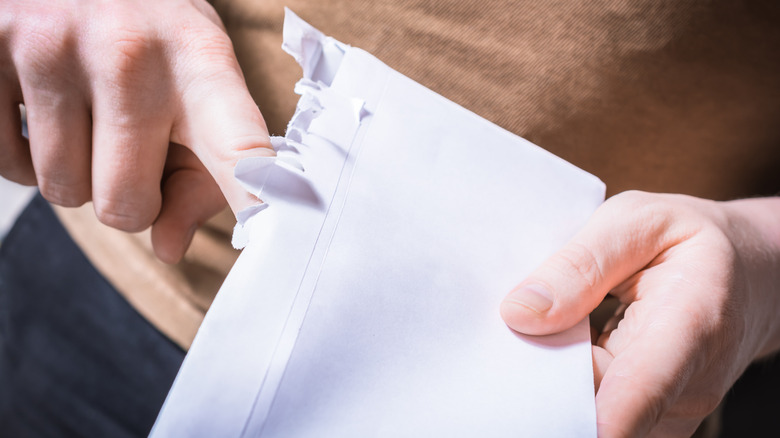person ripping open letter