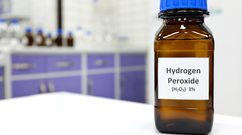 A bottle of hydrogen peroxide is in the foreground, with a blurry background