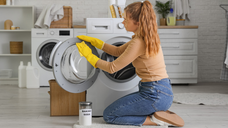 A woman is wiping down her washing machine with baking soda