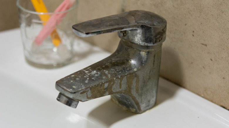 closeup on dirty bathroom faucet with rust and water spots