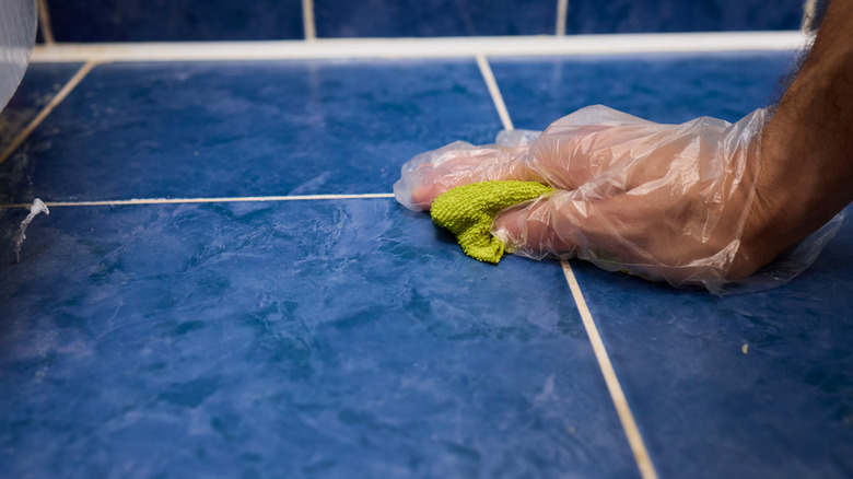person scrubbing grout with rag