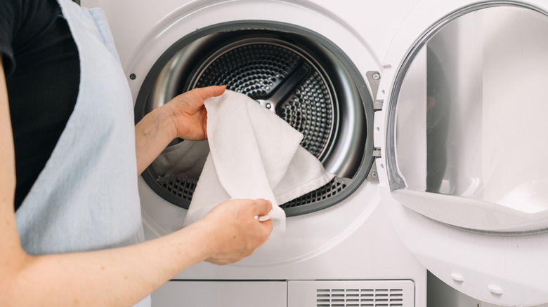 person removing white towel from dryer
