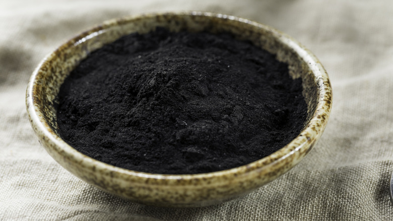 A bowl of activated charcoal sitting on a table runner.