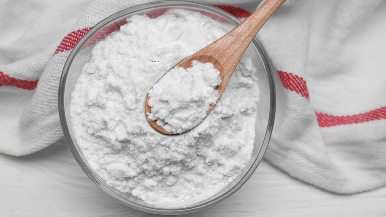 Cornstarch in a bowl with a wood spoon scooping it up