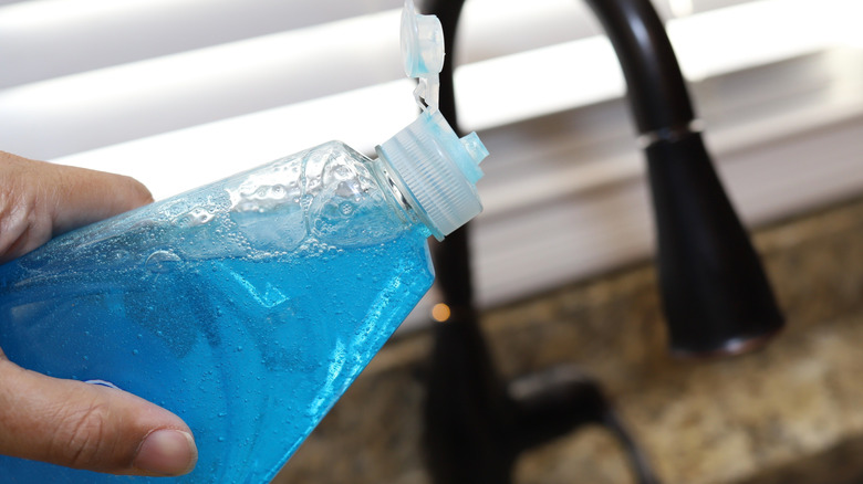 A person holds a bottle of dish soap