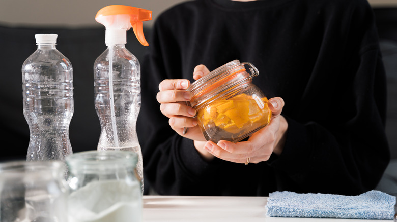 A person holding a jar of of homemade orange essential oil.
