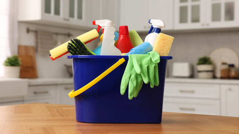 A bucket full of cleaning solutions sitting on a countertop in a kitchen.