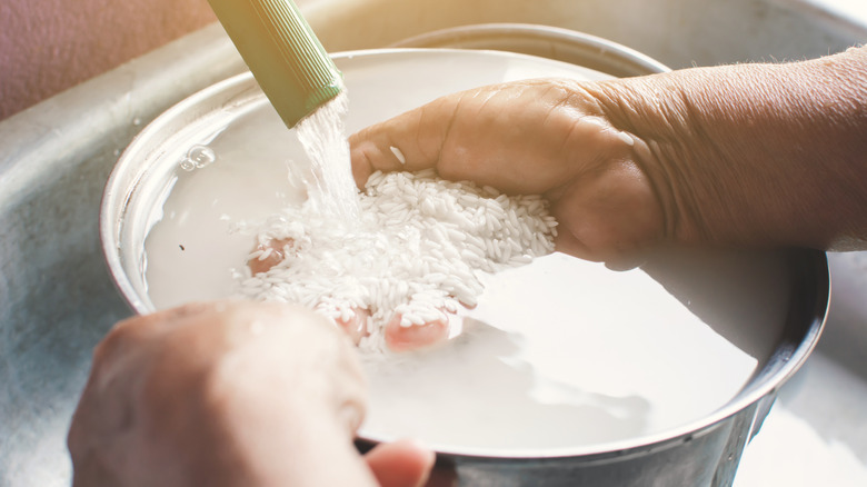 Hands washing rice and cloudy water floating to the top.