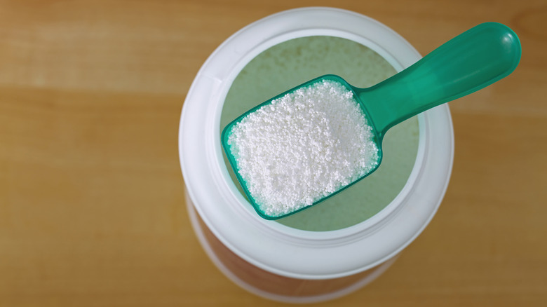A scoop of washing soda perched on top of an open bottle