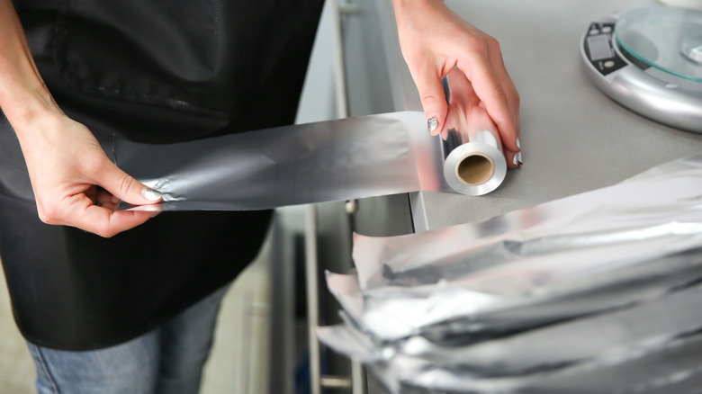 person tearing aluminum foil