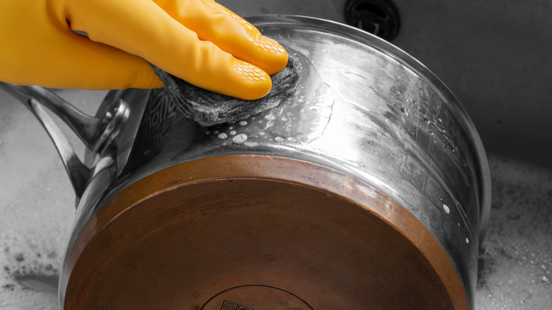 hands scrubing pot with scour