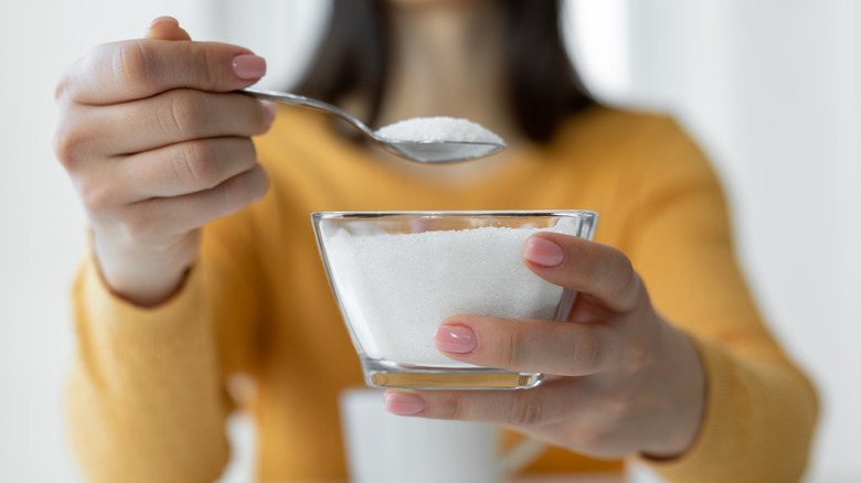 Person holding sugar in cup