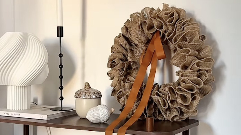 A wreath made from burlap, brown satin ribbon, and a wire coat hanger.