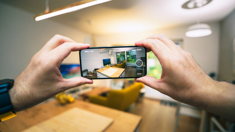 Hands holding smartphone taking pictures for selling apartment.
