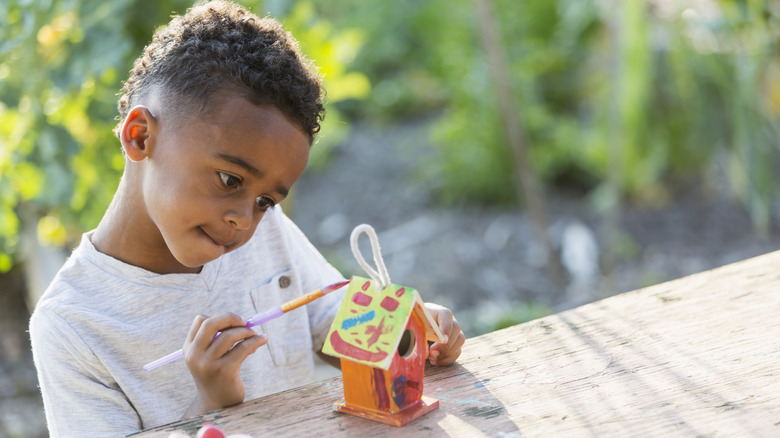 Child painting a birdhouse