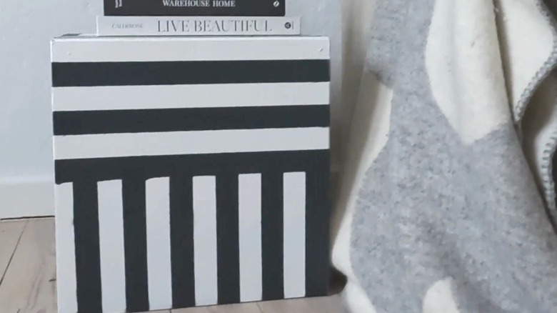 Striped black and white cube next to a bed