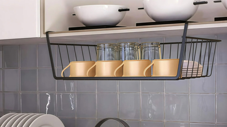 Black under-shelf wire storage basket holding dishes in a kitchen
