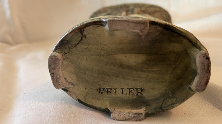 Underside of a pottery piece with the word WELLER stamped, a maker's mark for Weller Forest Pottery.