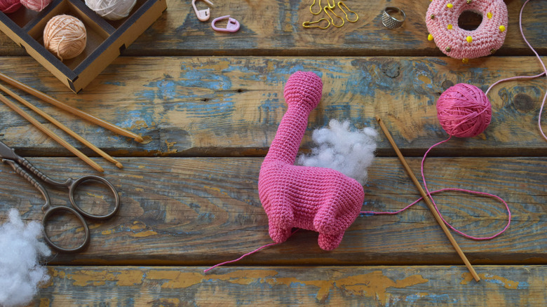 An unfinished crochet dinosaur with regular stuffing sticking out