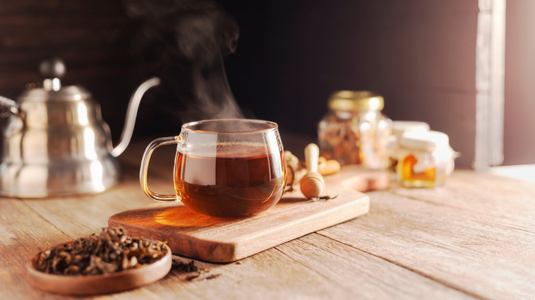 Mug of hot tea with loose tea leaves on a dish next to it.