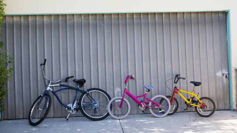Three bikes leaning against a garage door