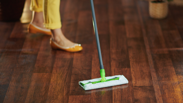 Someone using a Swiffer to clean hardwood floors