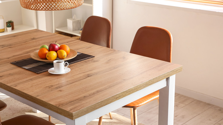 A plain dining room table with a plate of fruit on it.