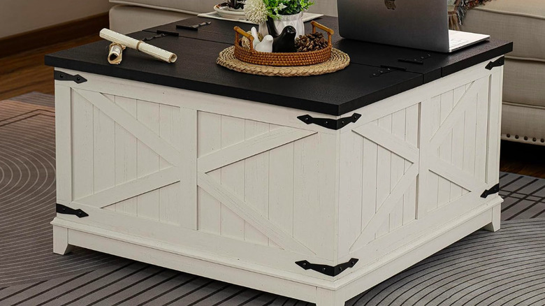 White barn-style coffee table with a laptop and other trinkets on it.