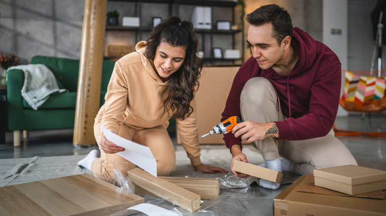 A couple assembles a coffee table in their living room