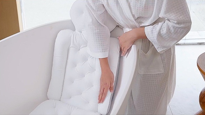 A person places the Voxor full-body bath pillow in a bathtub