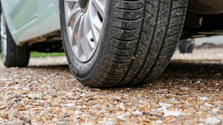 A close-up shot of a car parked on a gravel driveway