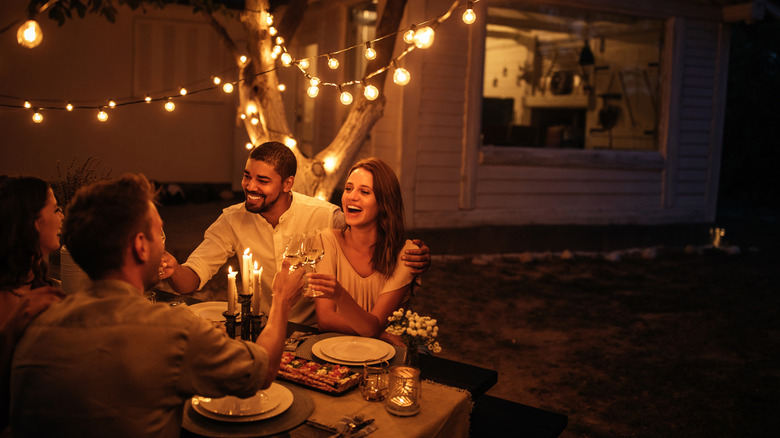 Friends having dinner in a yard with lights