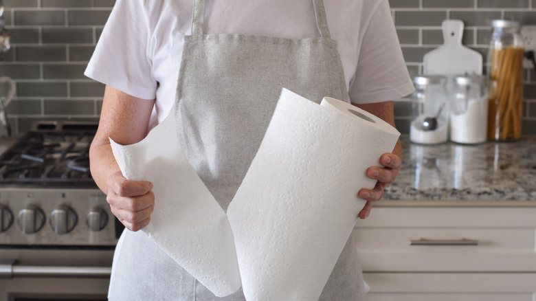 Person tearing a sheet off of a paper towel roll
