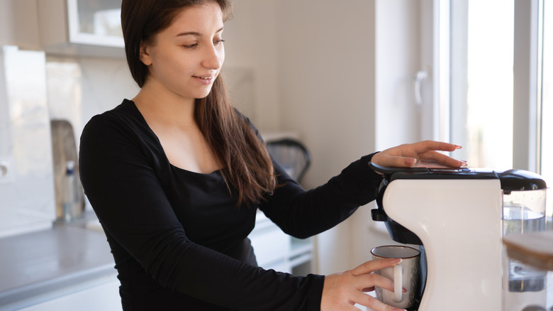 A woman making coffee with a single-serve coffee machine