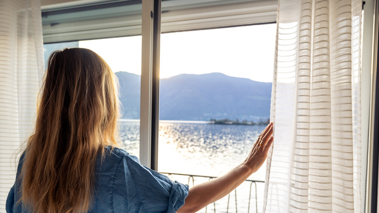 Woman standing at sliding glass door looking outside