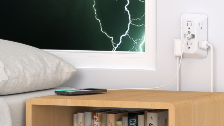 A white surge protector plugged in near a bed