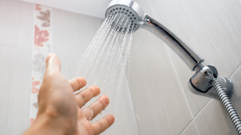 A hand testing water from a shower head