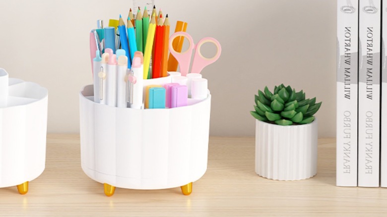 A white desk organizer filled with pens, pencils, markers, and scissor