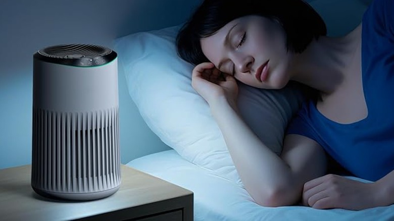 A small air filter on a table near a sleeping woman