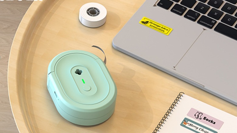 Nadaiin label maker machine on a table with laptop, tape, and a notebook
