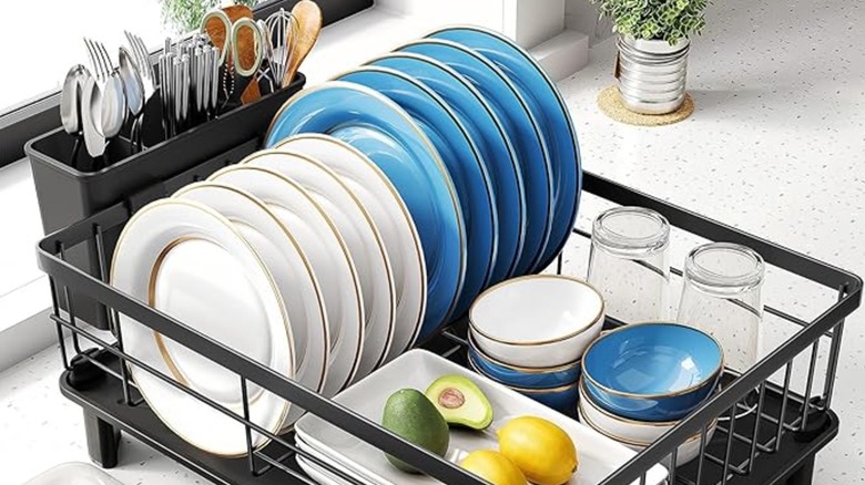 A small black dish drying rack holding cutlery and dinnerware